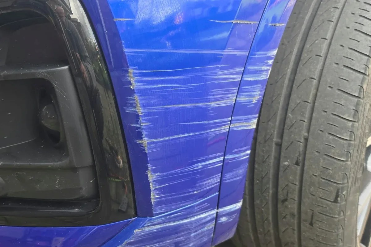 Corner of a blue bumper rubbed down to the plastic