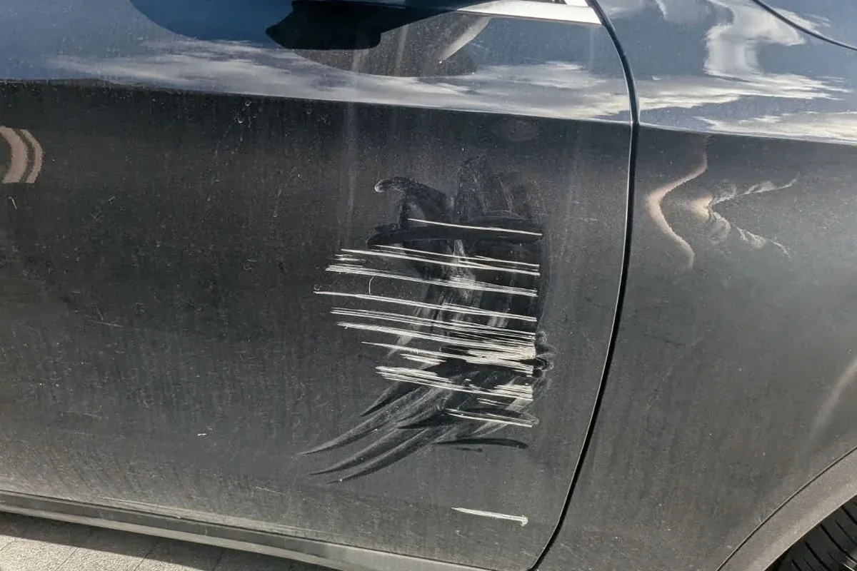 Black door with keyed lines and scrape marks through the paint